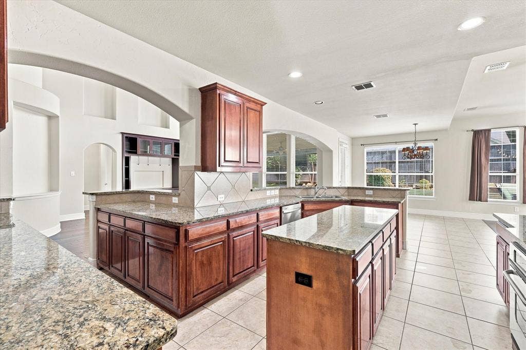 509 Wentworth Lane, Murphy, TX 75094 Expansive kitchen featuring granite countertops, wood cabinetry, tile flooring, recessed lighting, and a tile backsplash