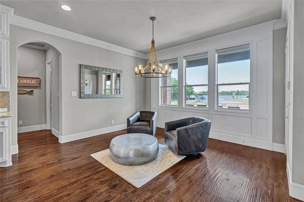 6412 Preferred Drive, Fort Worth, TX 76179 Spacious room featuring wood-finish flooring, a contemporary chandelier, multiple windows, and decorative wall paneling