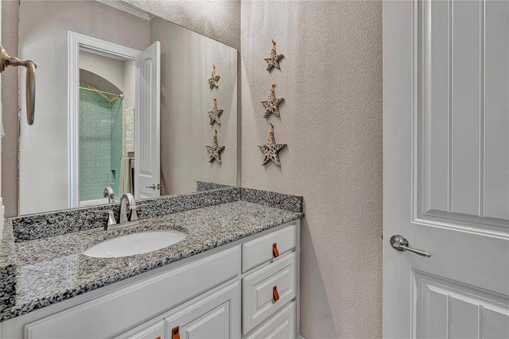 6412 Preferred Drive, Fort Worth, TX 76179 Bathroom vanity featuring a speckled countertop, undermount sink, and brushed nickel faucet