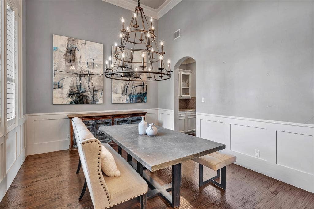 6412 Preferred Drive, Fort Worth, TX 76179 Dining area featuring wood-finish flooring, wainscoting, and an arched doorway leading to a built-in cabinet with glass-front doors