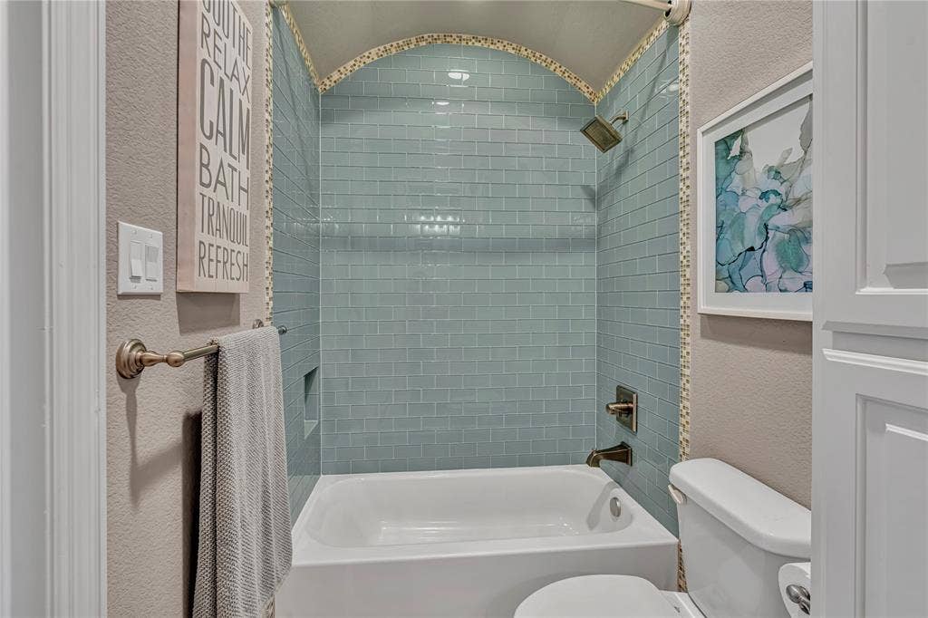 6412 Preferred Drive, Fort Worth, TX 76179 Bathtub and shower combination featuring subway tile surround in a light blue hue