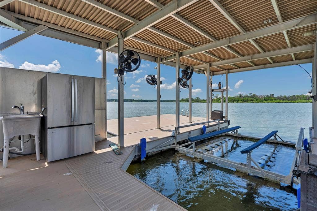 6412 Preferred Drive, Fort Worth, TX 76179 Covered boat dock featuring a boat lift, three ceiling-mounted fans, a stainless steel refrigerator, and a utility sink
