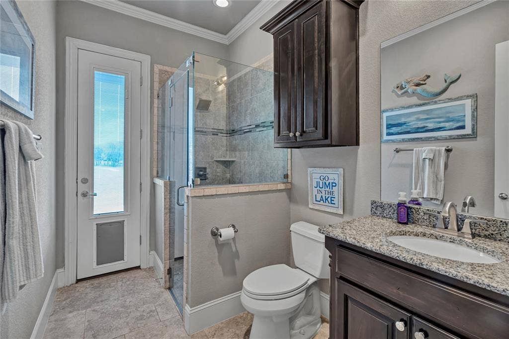 6412 Preferred Drive, Fort Worth, TX 76179 Bathroom featuring a walk-in glass shower enclosure, a single vanity with a speckled countertop, dark wood-finish cabinetry, and light gray wall paint