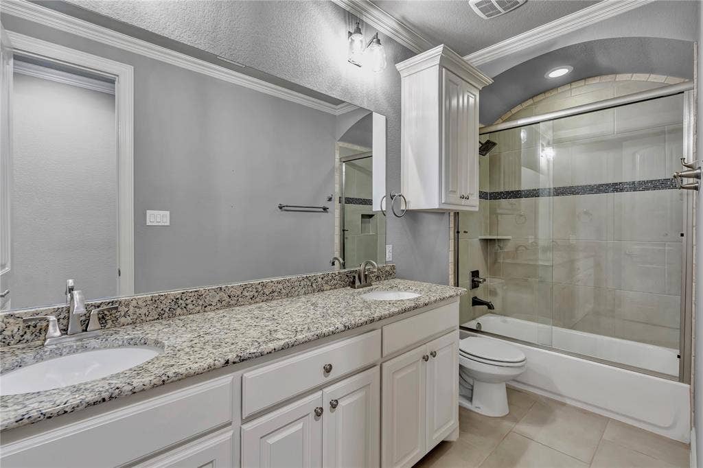 6412 Preferred Drive, Fort Worth, TX 76179 Bathroom featuring a double vanity with granite countertop, white cabinetry, and dual undermount sinks