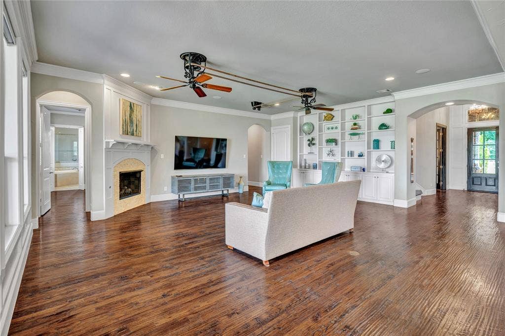 6412 Preferred Drive, Fort Worth, TX 76179 Spacious living area featuring wood-finish flooring, a corner fireplace with a stone surround, and extensive built-in shelving