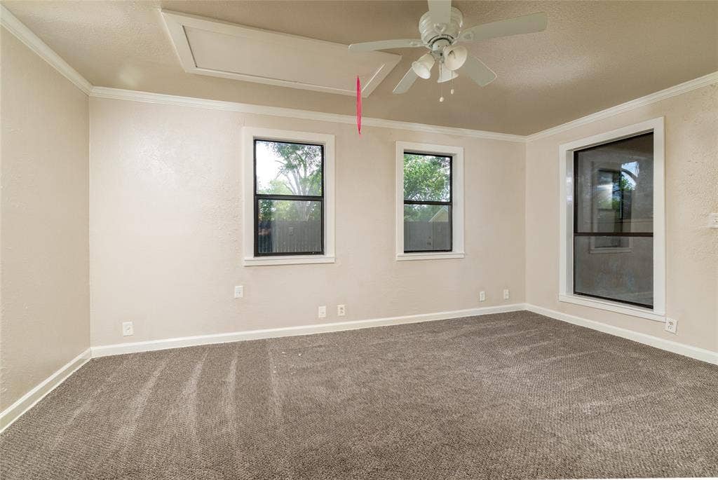 313 N Roe Street, White Settlement, TX 76108 Spacious room featuring new carpet, three windows, crown molding, and a ceiling fan with light fixture