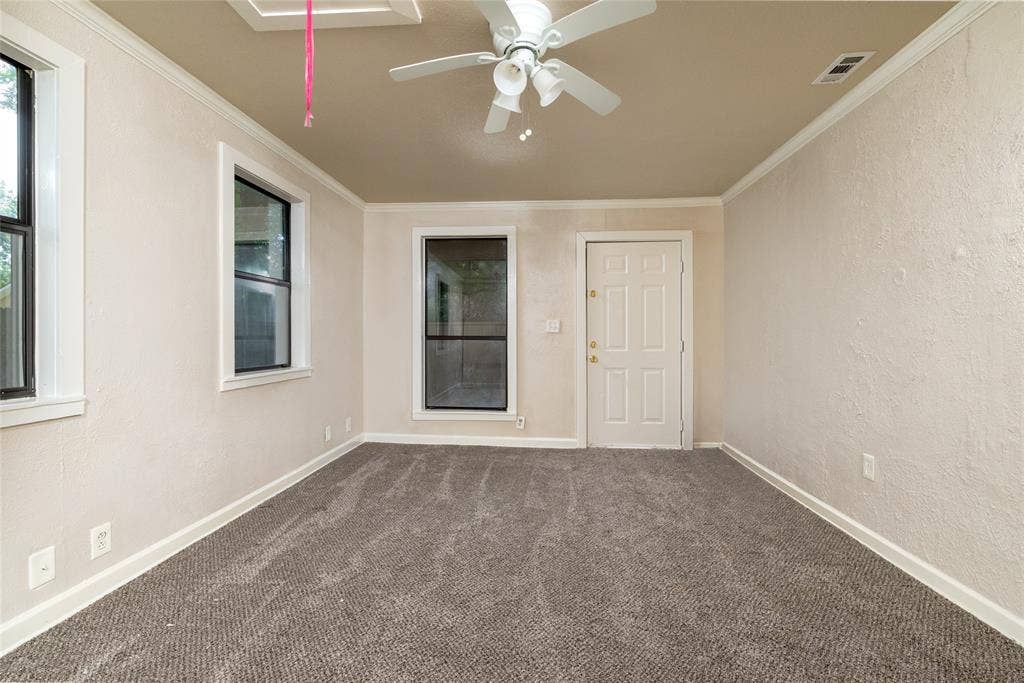 313 N Roe Street, White Settlement, TX 76108 Neutral-toned room featuring a textured wall finish, white trim, and a ceiling fan with integrated lighting