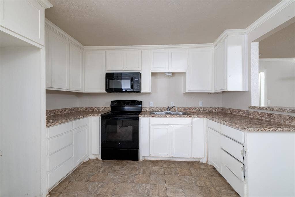 313 N Roe Street, White Settlement, TX 76108 Kitchen featuring white cabinetry with crown molding, laminate countertops, stainless steel sink, black range, and built-in microwave