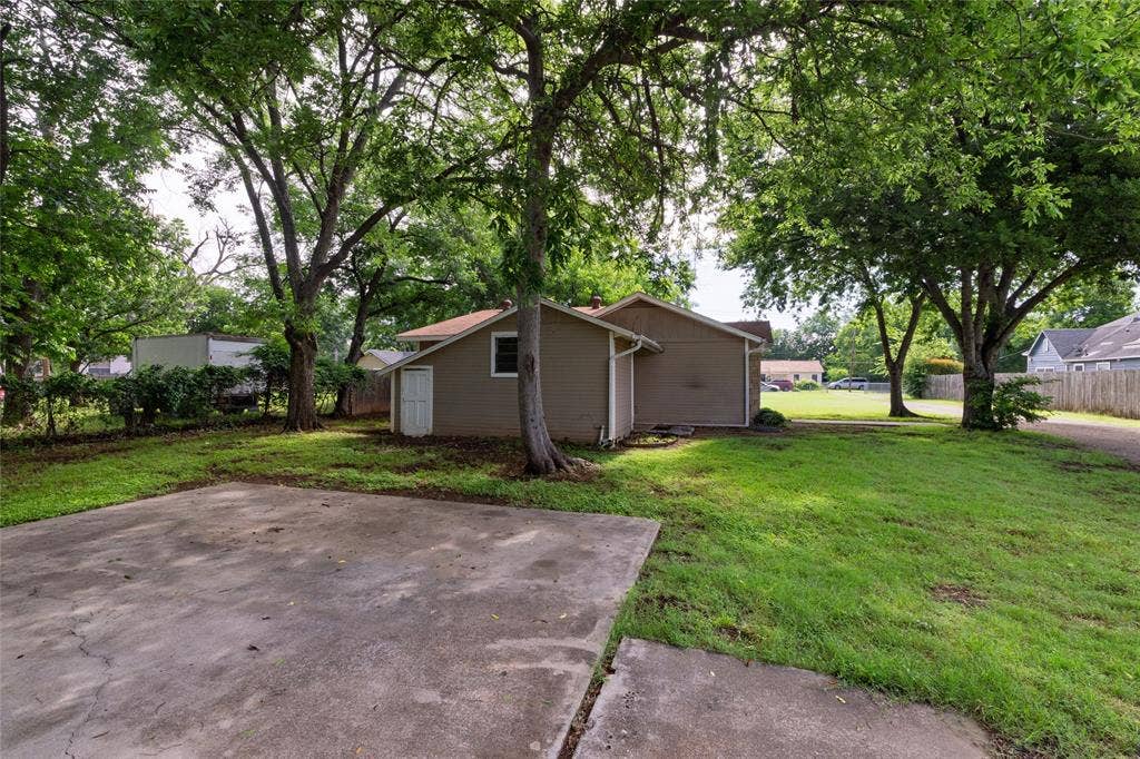 313 N Roe Street, White Settlement, TX 76108 Expansive concrete pad with surrounding green lawn and mature trees