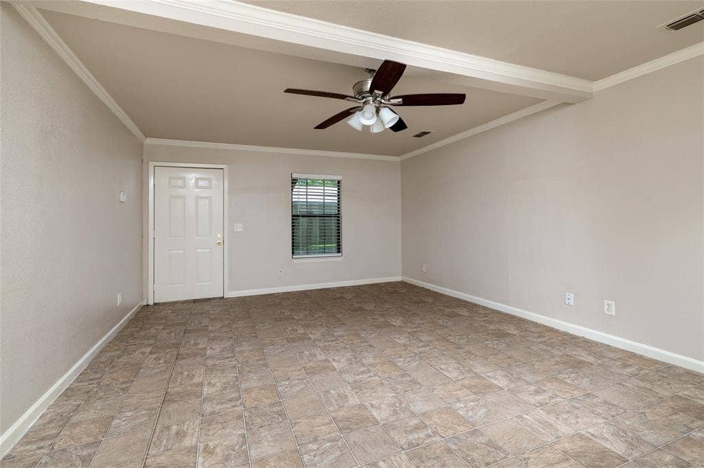 313 N Roe Street, White Settlement, TX 76108 Spacious room featuring tile flooring, a ceiling fan, crown molding, a window with blinds, and a paneled door