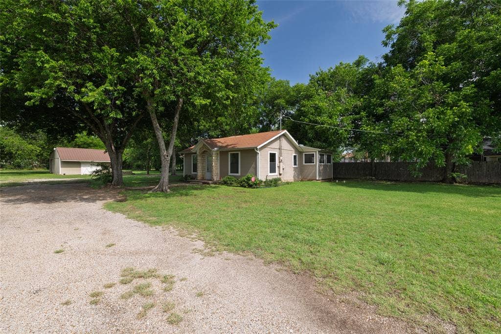 313 N Roe Street, White Settlement, TX 76108 Single-story residence featuring light-colored stucco siding, a warm brown shingle roof, and a stone facade entry
