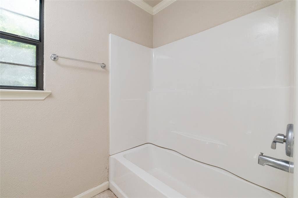 313 N Roe Street, White Settlement, TX 76108 Bathtub and shower combination featuring a white surround and chrome fixtures