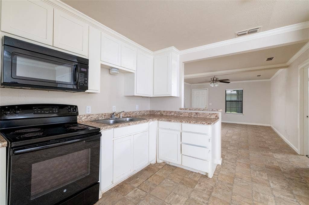 313 N Roe Street, White Settlement, TX 76108 Kitchen featuring white cabinetry, black appliances including a range and over-the-range microwave, and a double basin stainless steel sink