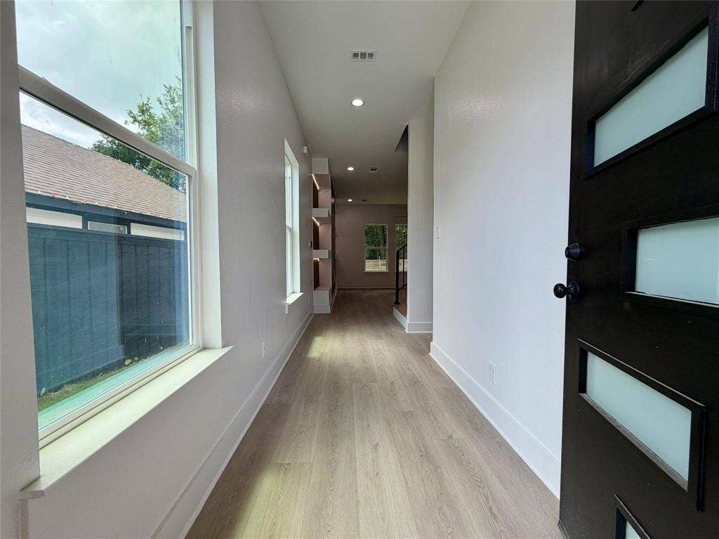 2823 Curvilinear Court, Dallas, TX 75227 Entryway featuring a contemporary black door with frosted glass inserts, wood-finish flooring, recessed lighting, built-in shelving, and white baseboards