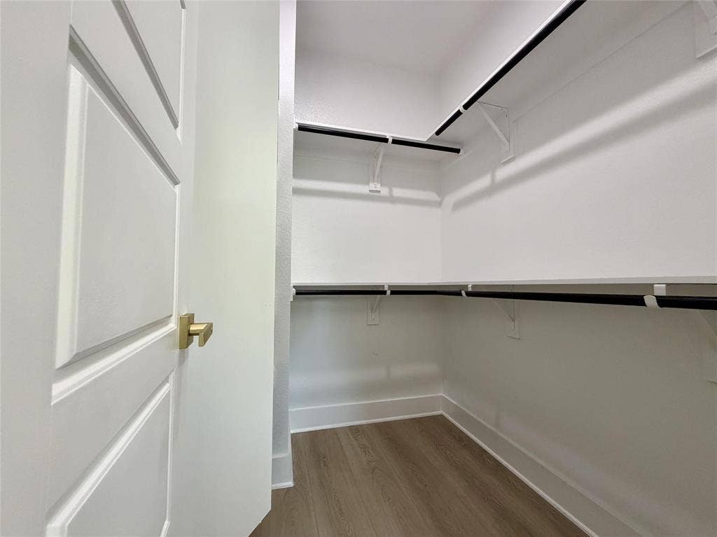 2823 Curvilinear Court, Dallas, TX 75227 Primary Walk-in closet featuring wood-finish flooring, white walls, and built-in shelving with hanging rods