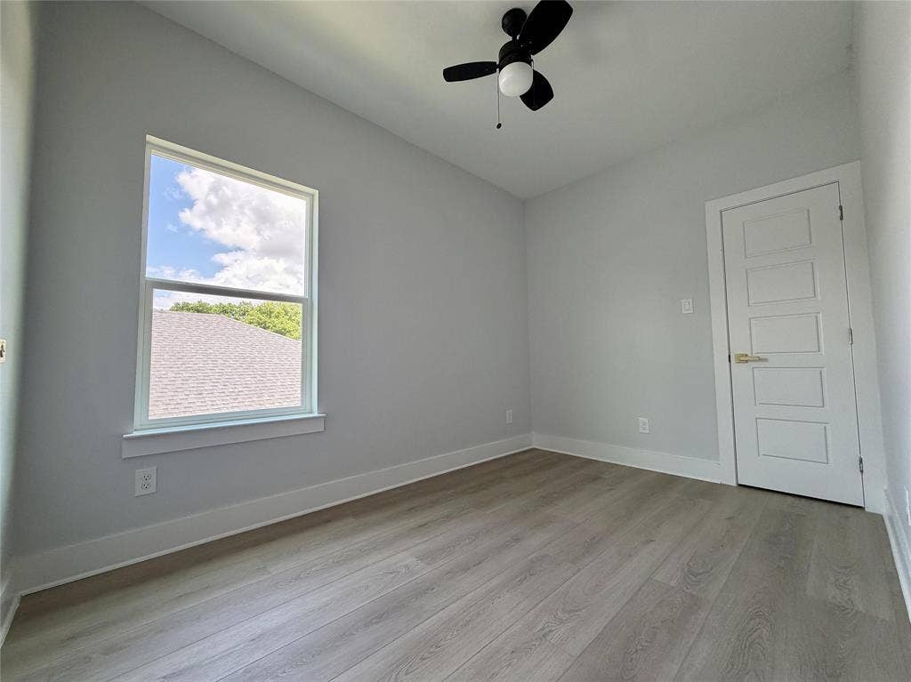 2823 Curvilinear Court, Dallas, TX 75227 Spacious 3rd bedroom or office featuring wood-finish flooring, a contemporary ceiling fan, and a single window providing natural light with closet