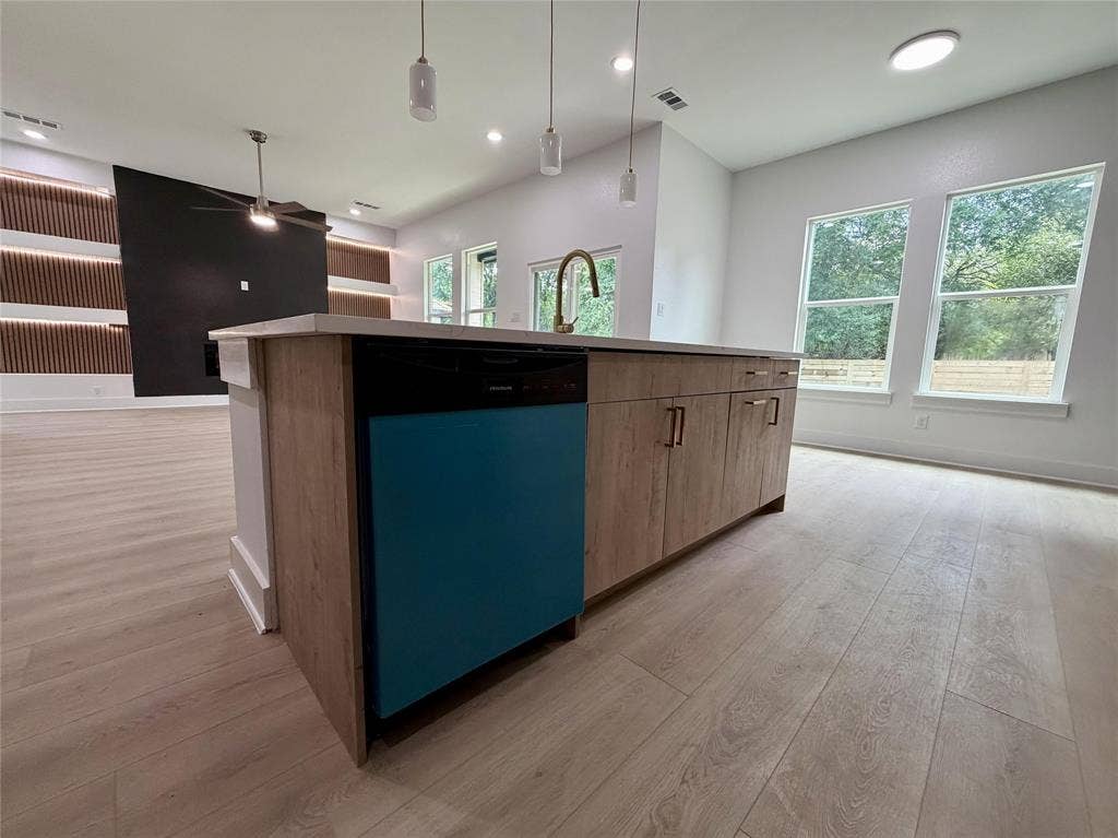 2823 Curvilinear Court, Dallas, TX 75227 Kitchen island featuring wood-finish cabinetry, a brass-finish faucet, and pendant lighting