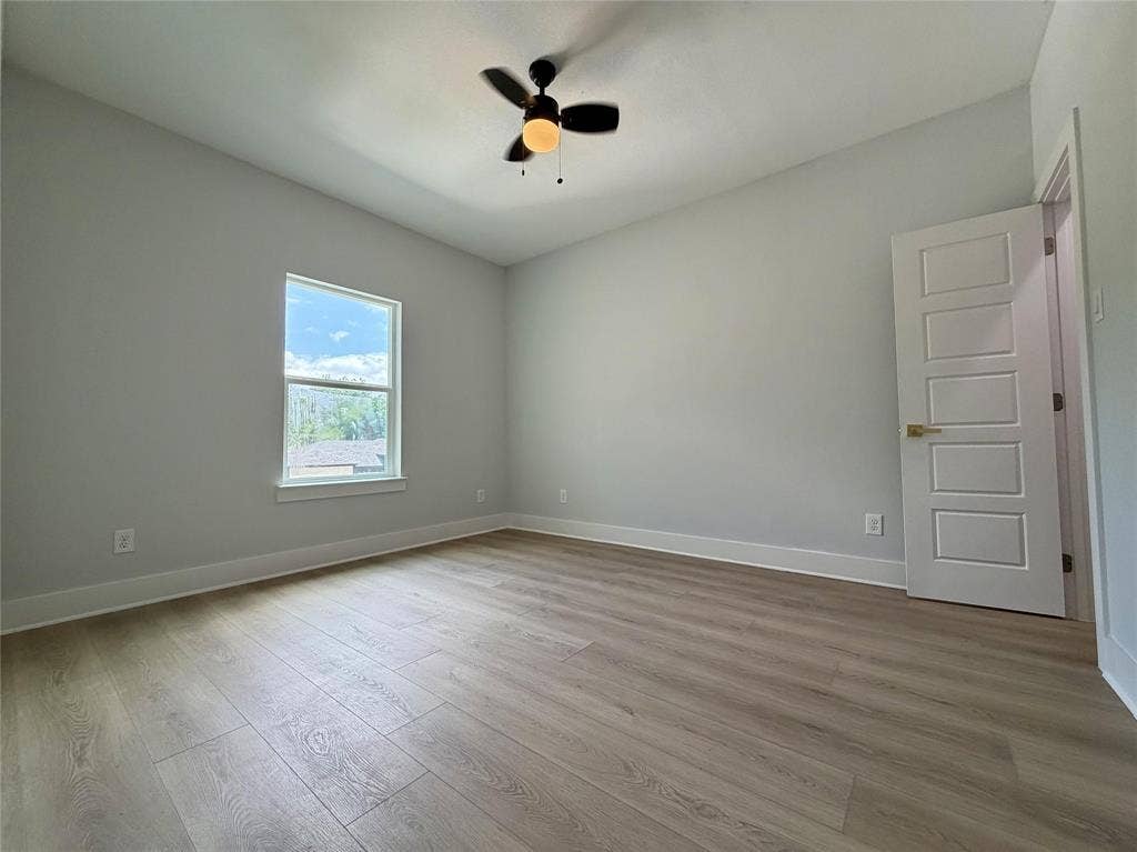 2823 Curvilinear Court, Dallas, TX 75227 Spacious 4th bedroom featuring wood-finish flooring, a contemporary ceiling fan with integrated lighting, a multi-pane window, and a modern five-panel interior door