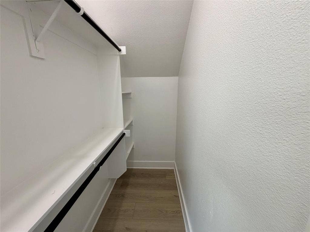 2823 Curvilinear Court, Dallas, TX 75227 Walk-in closet featuring built-in shelving, two hanging rods, white trim, and wood-finish flooring