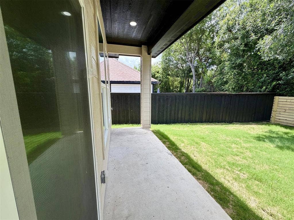 2823 Curvilinear Court, Dallas, TX 75227 Private outdoor space featuring a concrete patio, verdant lawn, and a dark-stained wood fence