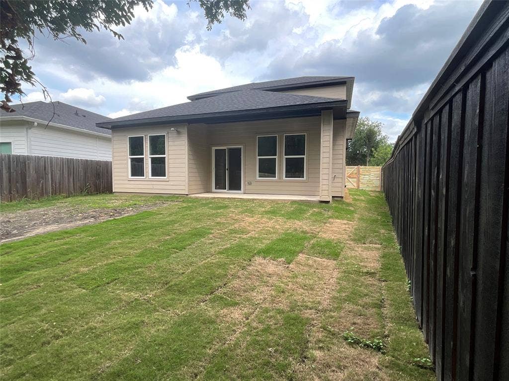 2823 Curvilinear Court, Dallas, TX 75227 Rear exterior featuring a tan siding facade, black shingle roof, and a concrete patio