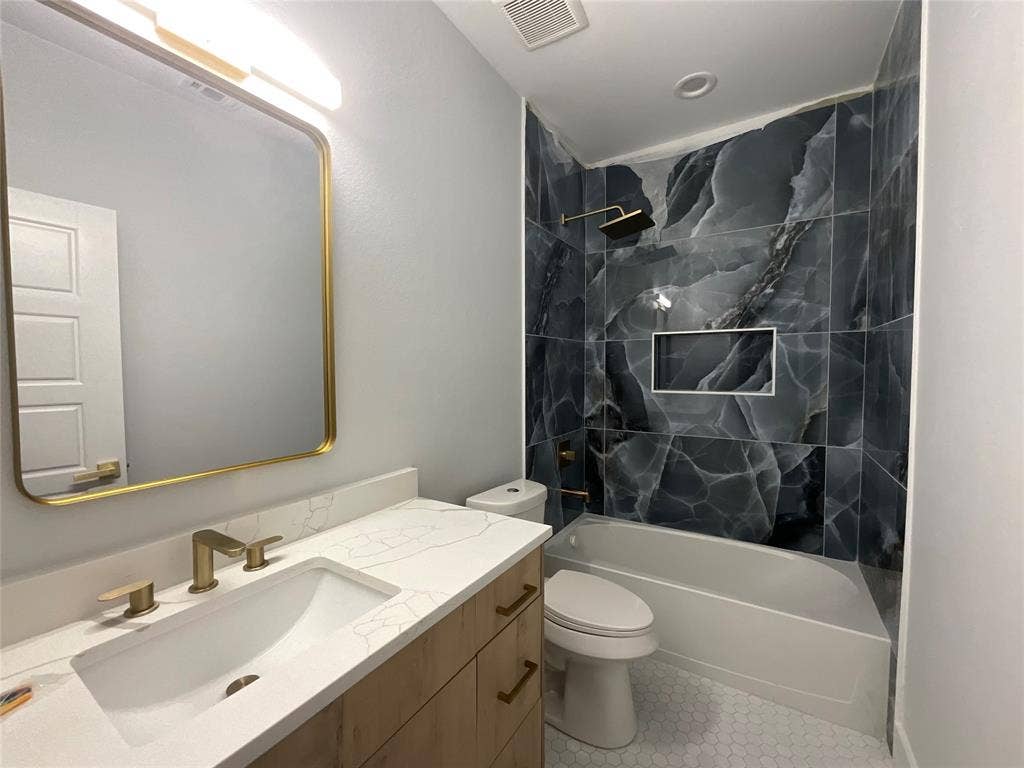 2823 Curvilinear Court, Dallas, TX 75227 Bathroom featuring a wood-finish vanity with a quartz countertop, an undermount sink with brass fixtures, and a gold-framed mirror