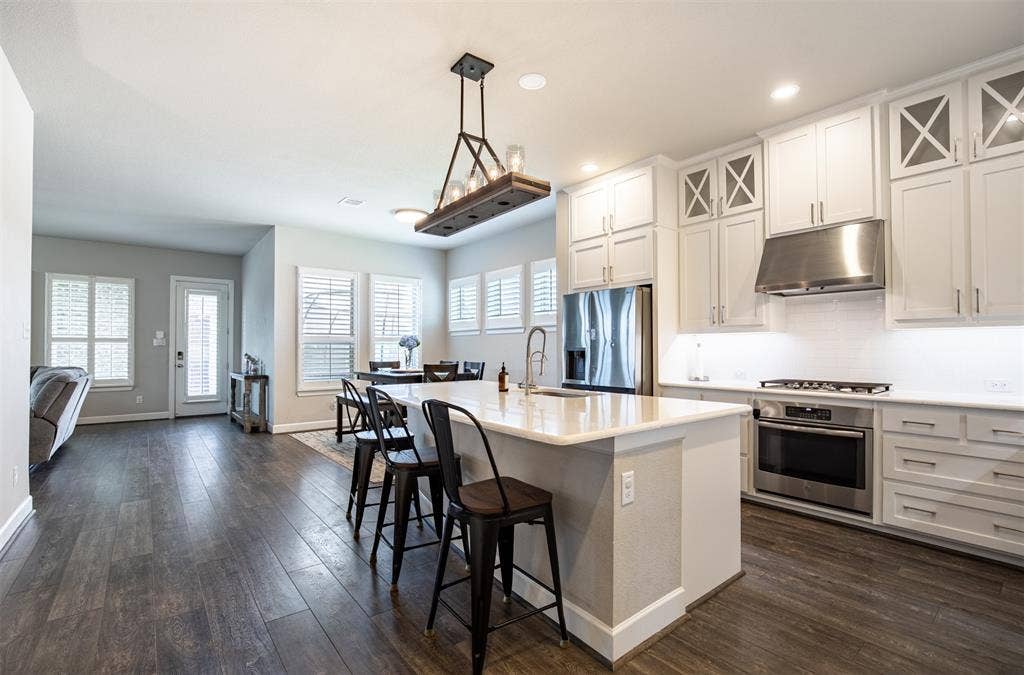 721 Matchbox Street, Argyle, TX 76226 Spacious kitchen highlighting custom full-height cabinets and elegant decorative feature lighting.