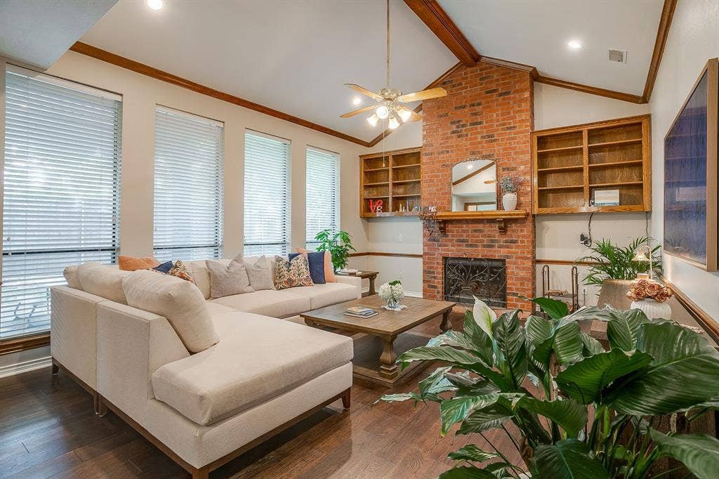 4624 Reunion Drive, Plano, TX 75024 Living area featuring a brick fireplace with an ornate screen, wood mantle, and built-in shelving