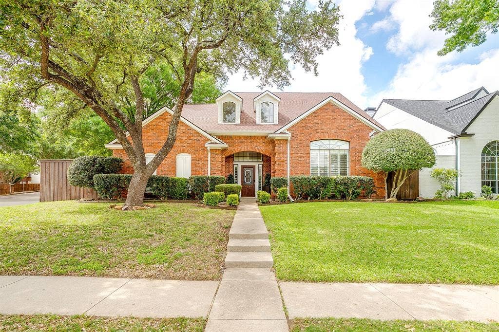 4624 Reunion Drive, Plano, TX 75024 Traditional brick exterior with an arched entry, a prominent front-facing window with shutters, and a dormer window
