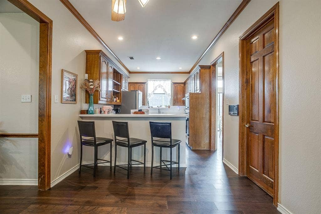 4624 Reunion Drive, Plano, TX 75024 Galley kitchen featuring wood-finish cabinetry, a white countertop, and a breakfast bar
