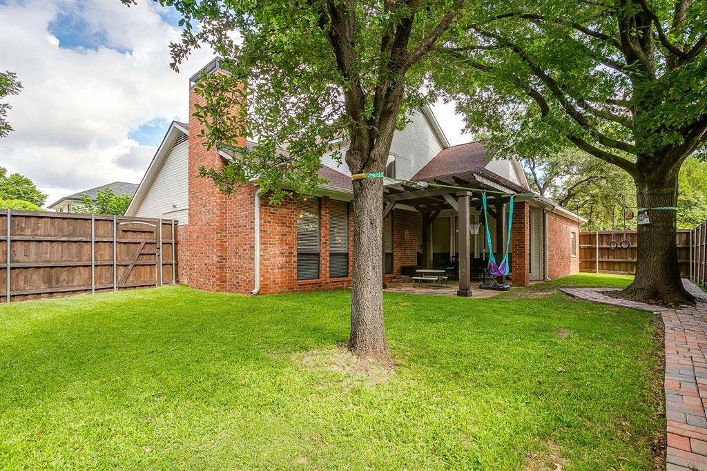 4624 Reunion Drive, Plano, TX 75024 Spacious backyard featuring a covered patio, extensive lawn, mature trees, brick paver walkway, and privacy fencing