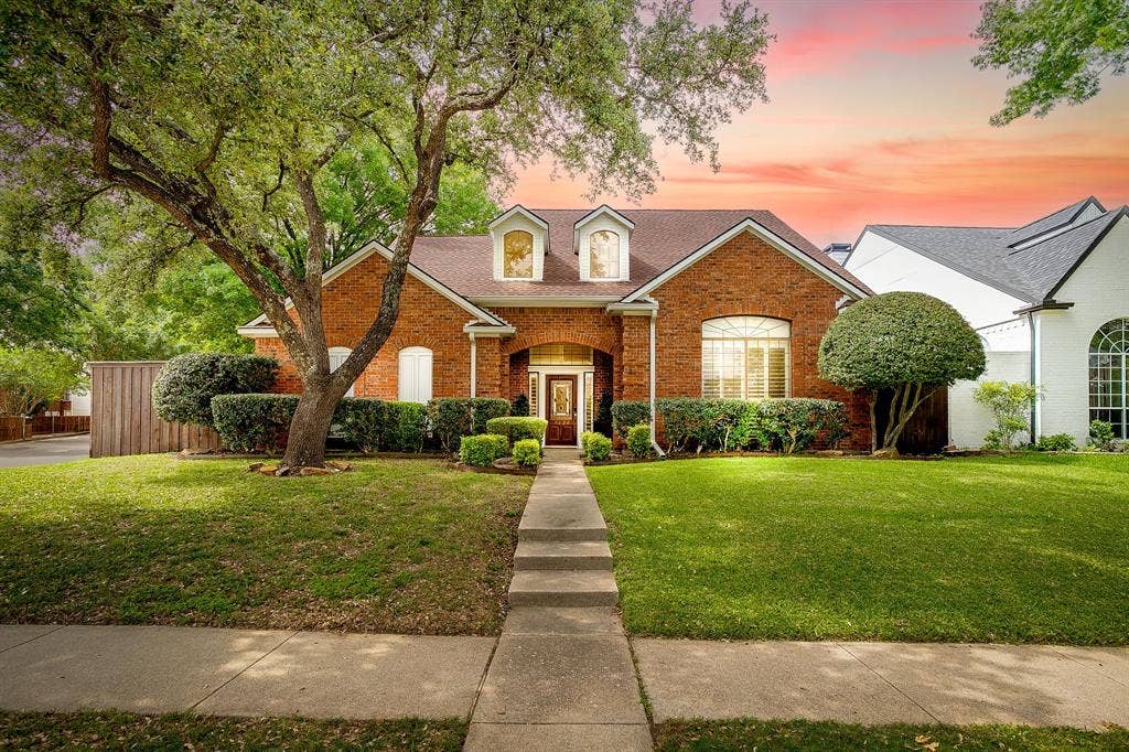 4624 Reunion Drive, Plano, TX 75024 Brick exterior with dormer windows, a prominent front tree, manicured hedges, and a concrete walkway