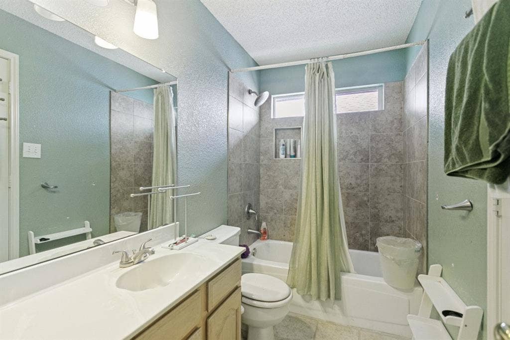 6713 Ashglen Place, Plano, TX 75023 Bathroom featuring a white vanity with integrated sink, brushed nickel faucet, large wall mirror, and a tiled shower/tub combination with built-in niche and transom windows