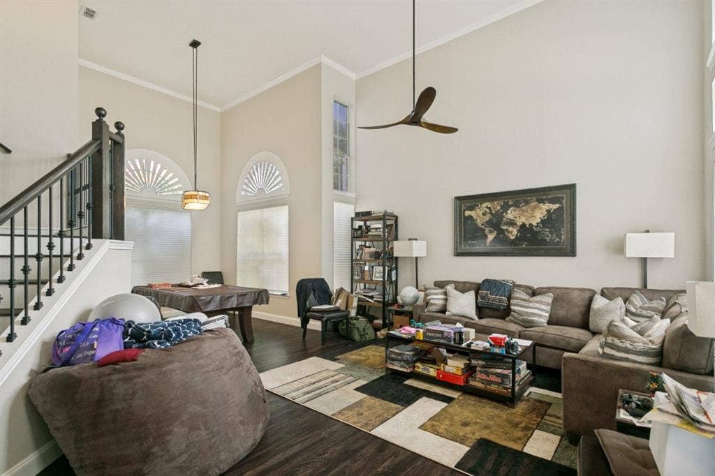 6713 Ashglen Place, Plano, TX 75023 Two-story living area featuring a dark wood-finish staircase with wrought iron balusters, vaulted ceilings, arched transom windows, and dark wood-finish flooring