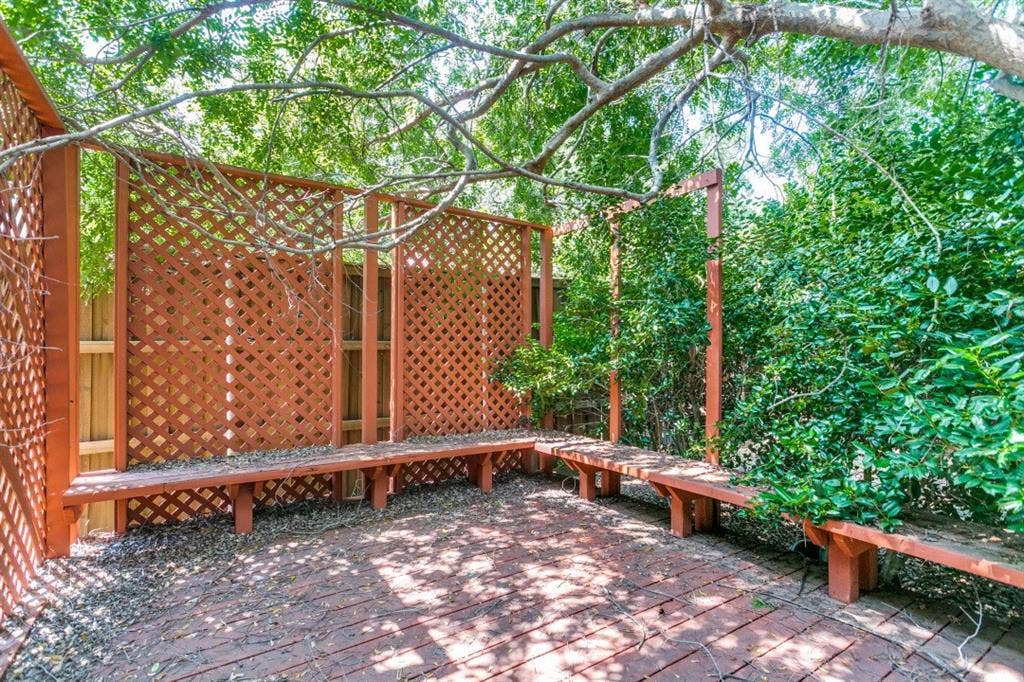 6713 Ashglen Place, Plano, TX 75023 Private outdoor area featuring a brick patio, built-in wood benches, decorative lattice screens, and mature foliage
