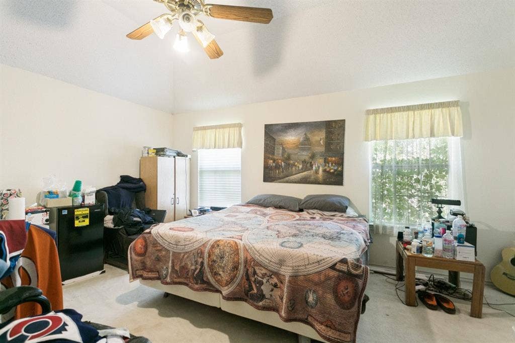 6713 Ashglen Place, Plano, TX 75023 Vaulted ceiling featuring a ceiling fan with light fixture, two windows with blinds, and neutral carpet flooring