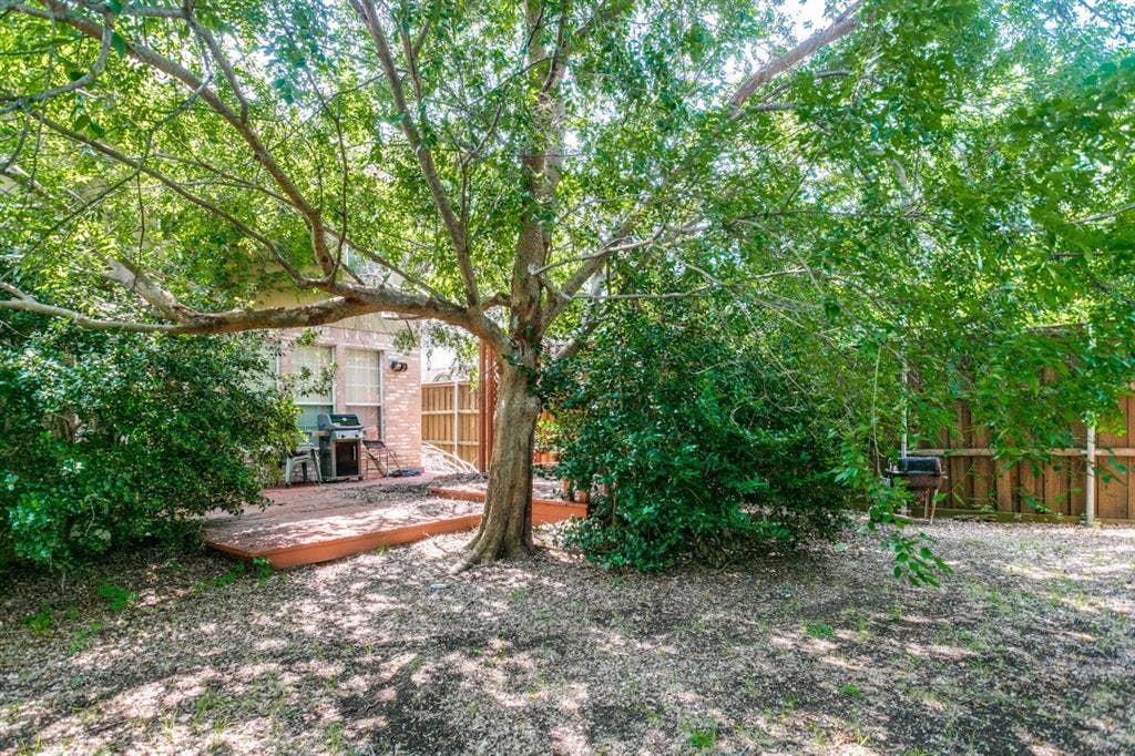 6713 Ashglen Place, Plano, TX 75023 Secluded backyard featuring a mature shade tree, a wooden deck, a privacy fence, and brick exterior