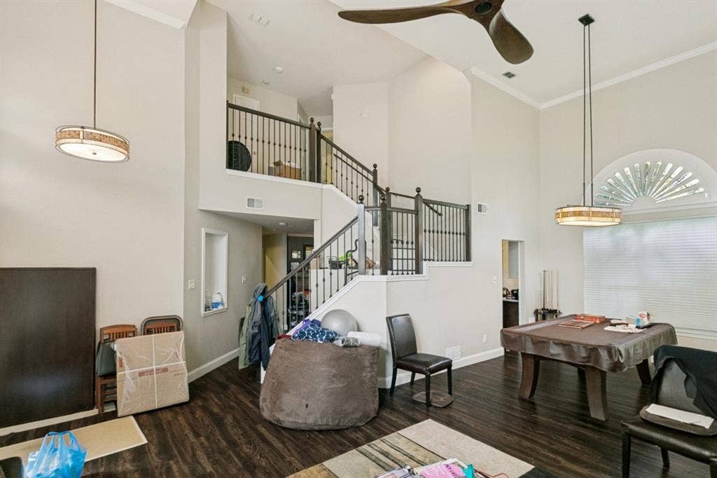 6713 Ashglen Place, Plano, TX 75023 Two-story living area featuring wood-finish flooring, a grand staircase with dark iron balusters, high ceilings, and crown molding