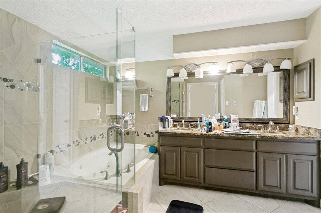 6713 Ashglen Place, Plano, TX 75023 Expansive bath featuring a glass-enclosed shower, built-in jetted tub, dual vanity with undermount sinks, and a large wall-mounted mirror