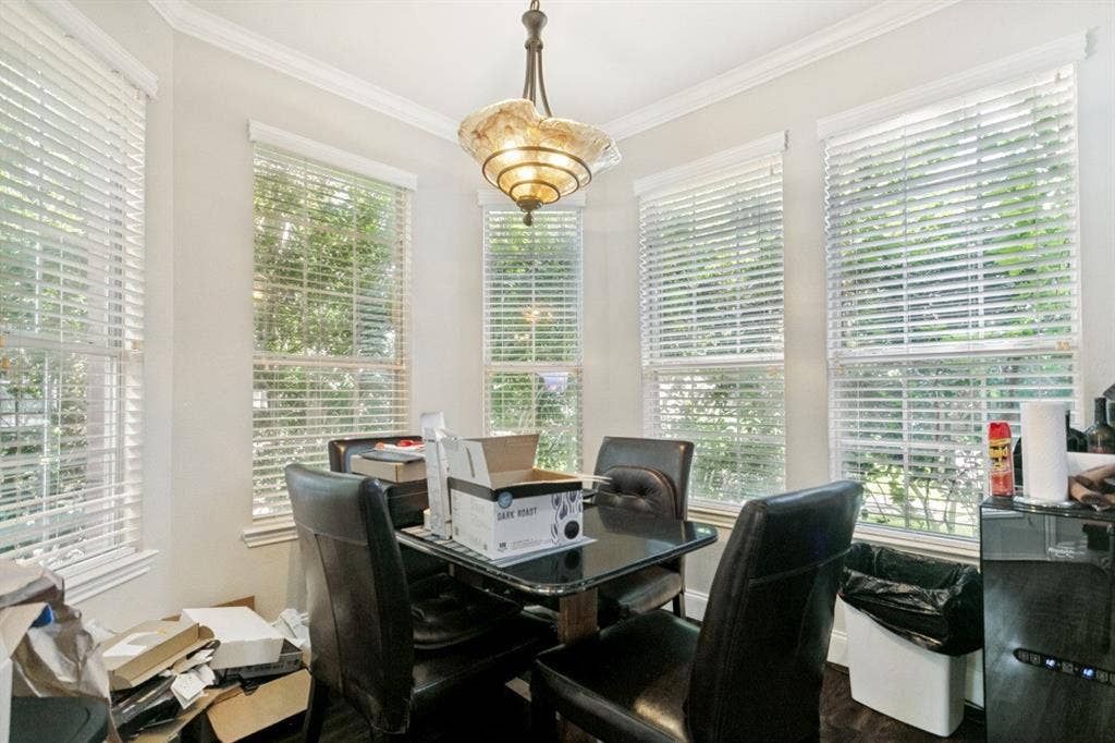 6713 Ashglen Place, Plano, TX 75023 Bay window area featuring five vertical windows with blinds, a multi-tiered chandelier, crown molding, and light-toned wall paint
