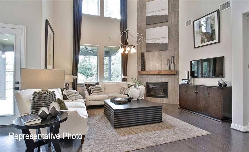 1324 Gardendale Hollow Lane, Anna, TX 75409 Living area featuring high ceilings, dark wood-finish flooring, a contemporary fireplace with a wood mantel, and large windows