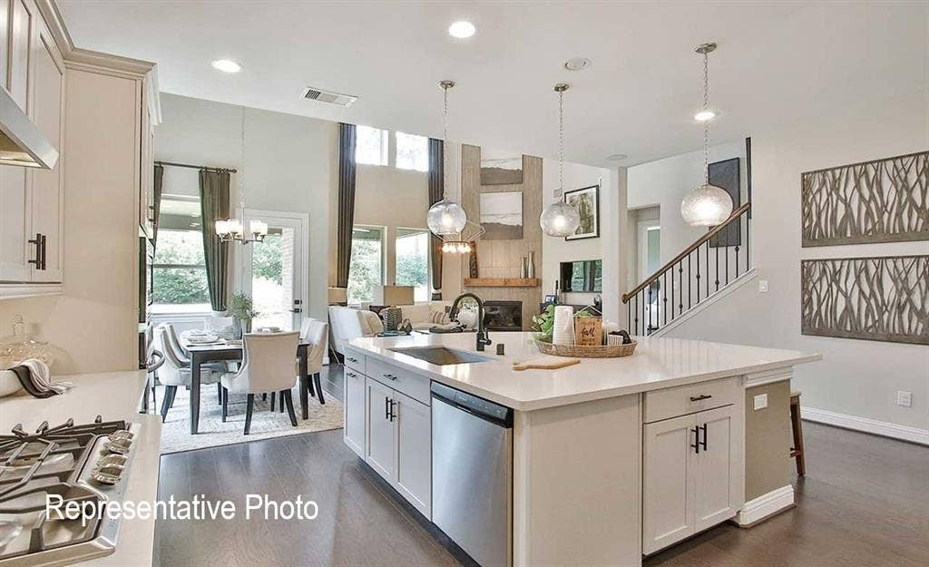 1324 Gardendale Hollow Lane, Anna, TX 75409 Open-concept kitchen featuring a large central island with seating, stainless steel appliances, pendant lighting, and wood-finish flooring throughout