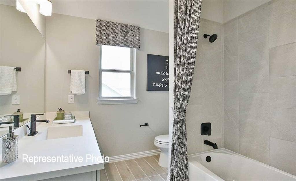 1324 Gardendale Hollow Lane, Anna, TX 75409 Contemporary bathroom featuring a single-sink vanity with dark hardware, a framed mirror, and a tub-shower combination with light-toned wall tiling