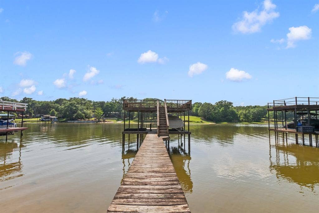 194 Bushwhacker Drive, Mabank, TX 75156 Covered boathouse featuring a boat lift, dual personal watercraft lifts, and party deck.