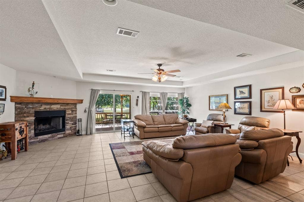 194 Bushwhacker Drive, Mabank, TX 75156 Open-concept living area with vaulted ceilings, abundant natural light, and a stone wood-burning fireplace.