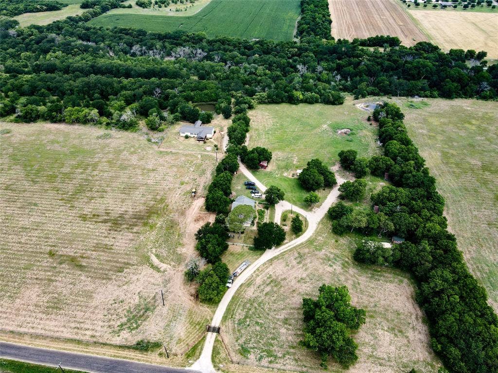 2749 Mcgregor South Loop, McGregor, TX 76657 Expansive rural property featuring multiple cleared areas, established tree lines, a single-story residence, and a pond