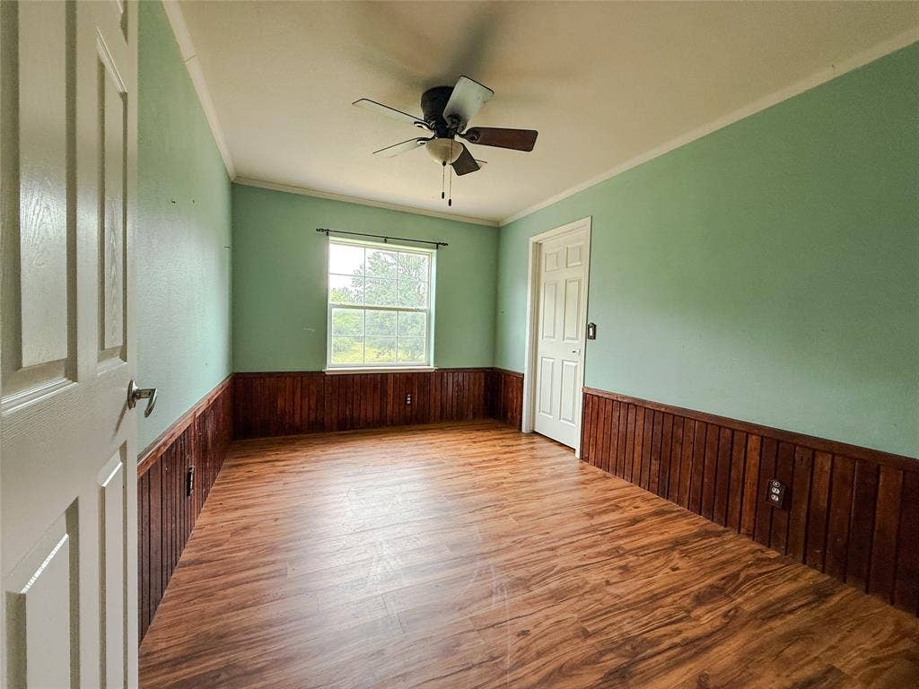 2749 Mcgregor South Loop, McGregor, TX 76657 Bright interior featuring wood-finish flooring, wood paneling, a ceiling fan, and a paneled door