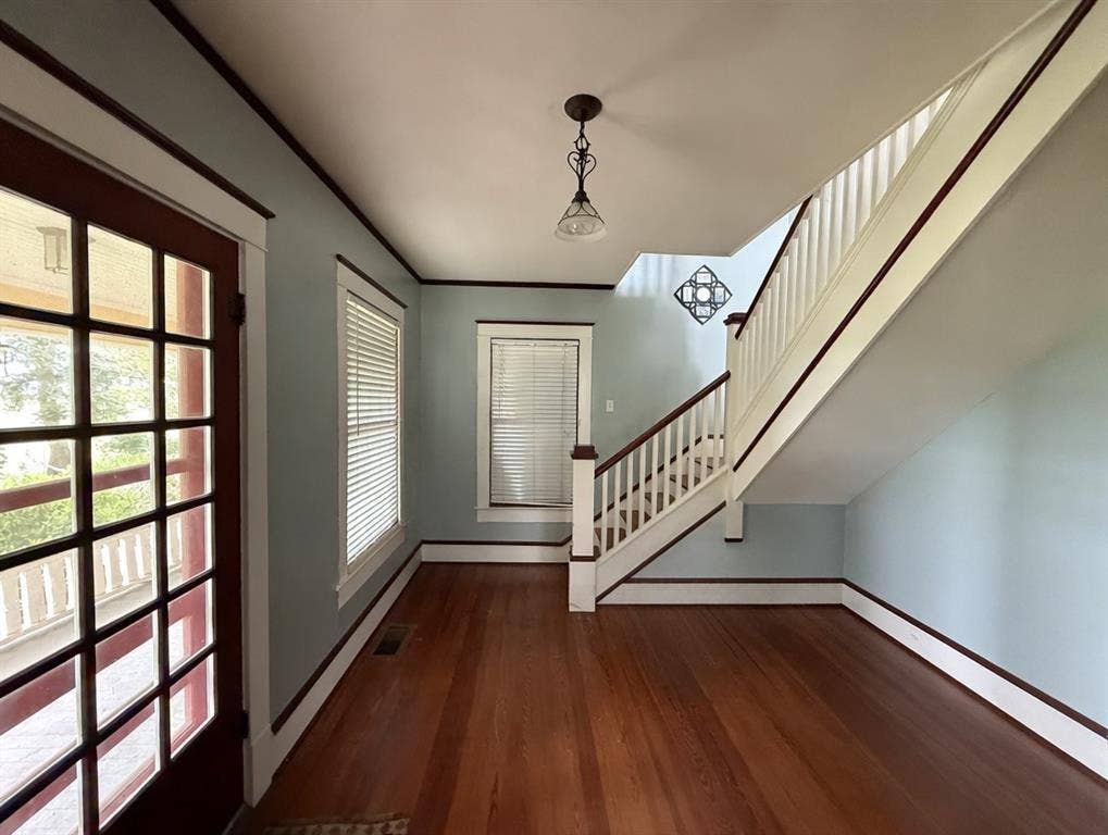 2749 Mcgregor South Loop, McGregor, TX 76657 Entryway featuring wood-finish flooring, a classic staircase with dark wood handrails, a paneled door with multiple glass lites, and crisp white trim against light blue walls