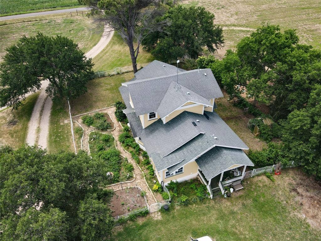 2749 Mcgregor South Loop, McGregor, TX 76657 Expansive property featuring a two-story residence with a covered porch, established trees, and multiple garden beds
