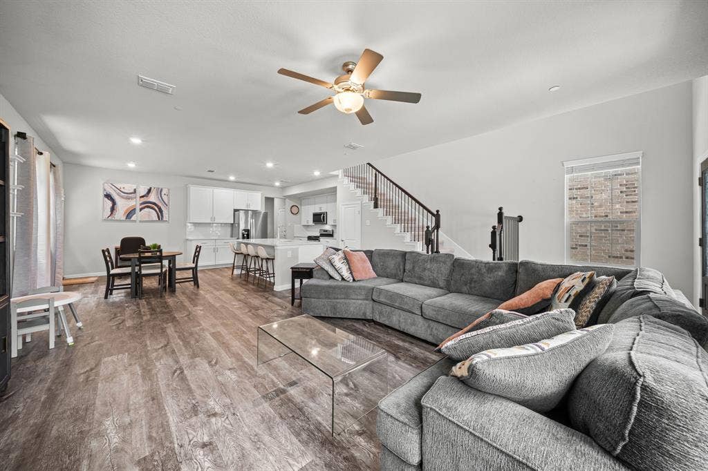 4129 Bullwhip Creek Lane, Sachse, TX 75048 Open-concept living space featuring wood-finish flooring, recessed lighting, a ceiling fan, and a staircase with dark wood railings